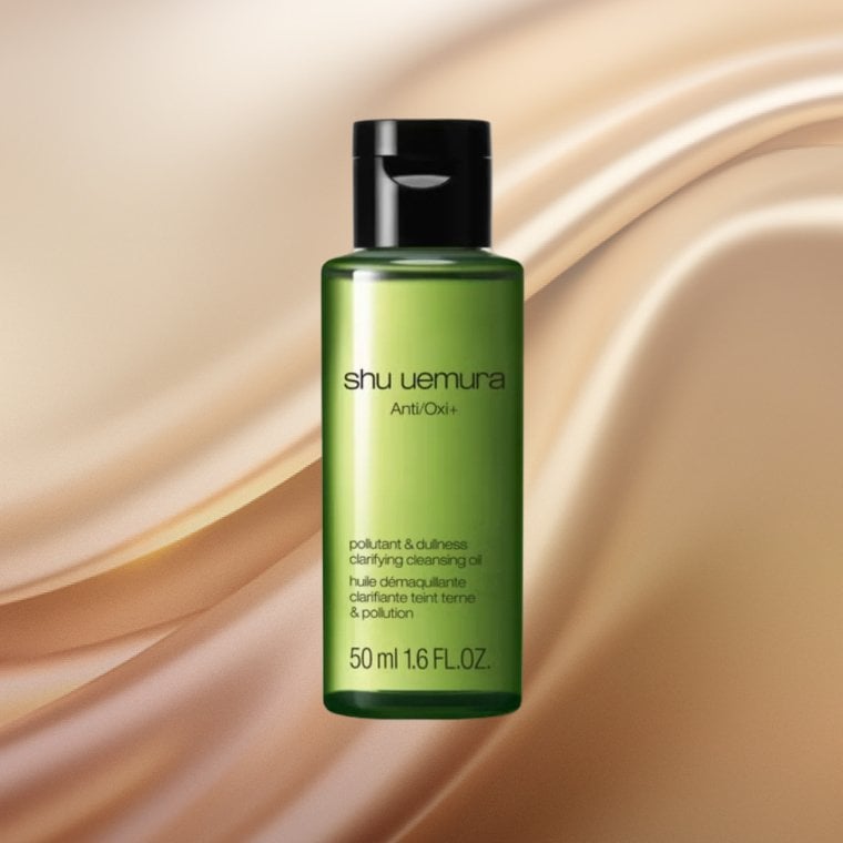 Bottle of Shu Uemura Anti/Oxi+ Pollutant & Dullness Clarifying Cleansing Oil on a textured background