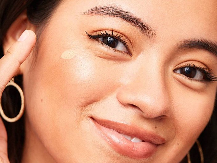 photo of person applying foundation and smiling