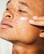 Person applying moisturizer to their cheek