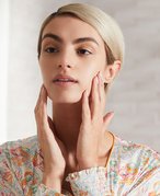 Image of a woman with short blonde hair touching the sides of her face while looking in the mirror