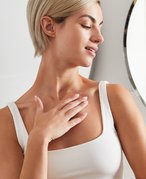 person in white tank top touching collarbone