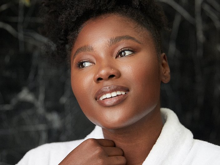 person smiling toward camera holding the side of their collar on a robe