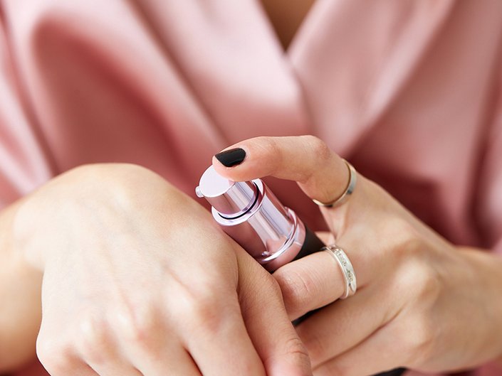 Close-up picture of someone applying makeup primer to the back of their hand