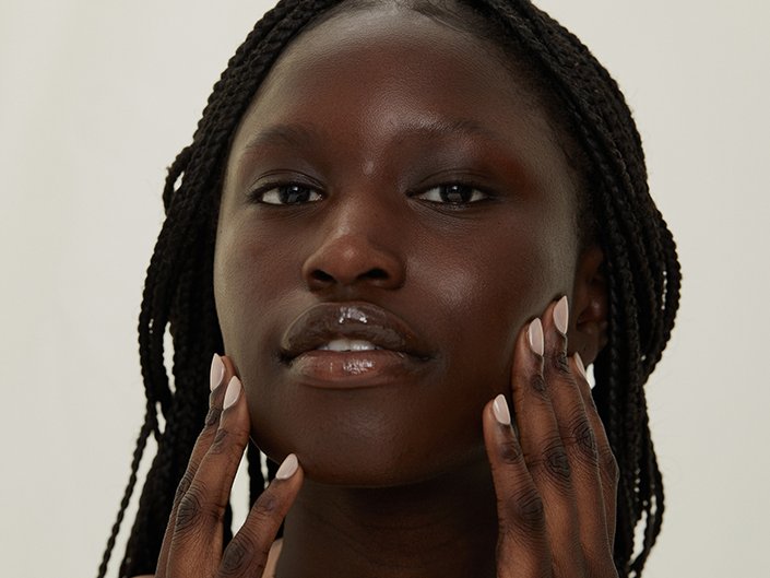 Picture of a model touching the sides of their face, looking at the camera