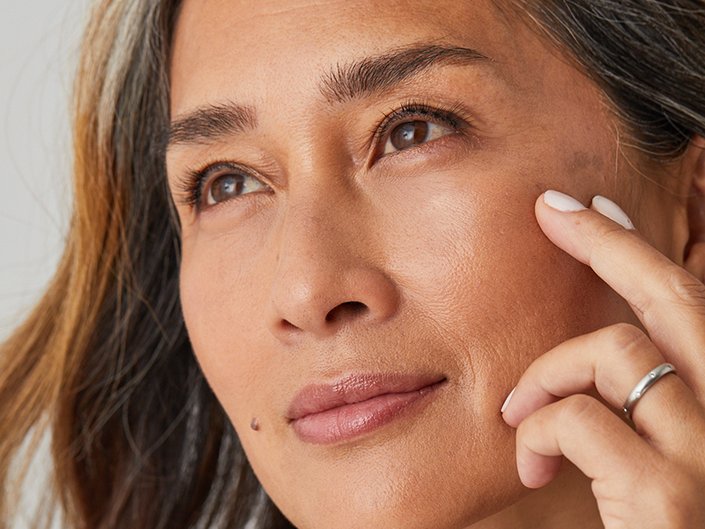 Person touching their middle finger and pointer finger to their cheekbone near the outer corner of their eye