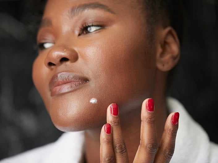 Photo of a model applying a spot treatment to her chin