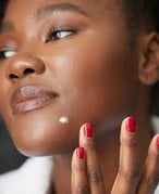 Photo of a model applying a spot treatment to her chin