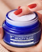 Close-up picture of a person with red nails holding the IT Cosmetics Confidence in Your Beauty Sleep Night Cream