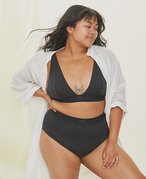 Person with long dark hair wearing a black bra and underwear with a white robe