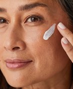 Close-up of a person's face with cream swatched on their cheek