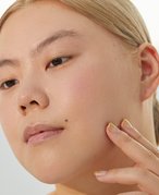 Picture of a person looking out of frame and lightly touching their chin