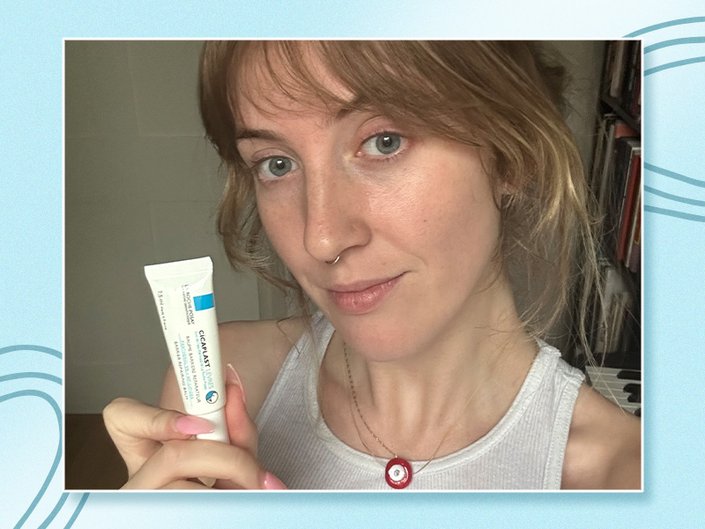 Photo of the editor holding the La Roche-Posay Cicaplast Lips Hydration Restore Lip Balm against a light blue graphic background