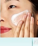 Close-up of a person’s hands rubbing facial cleanser into skin