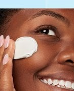 A woman rubbing a lotion into her face