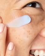 A person applying a cream to their face