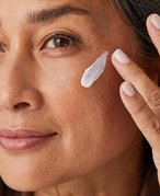 Image of a woman applying moisturizer to her cheek