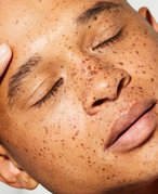 person touching face with closed eyes facing toward the camera