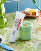 Bathroom countertop with hair brush, toothbrush in a cup, and Kiehl's Ultra Facial Advanced Repair Barrier Cream